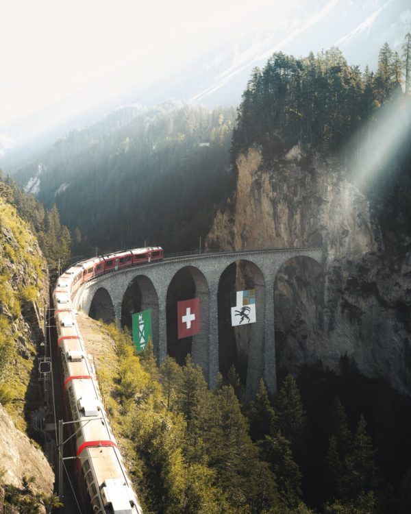 red train on rail near mountain during daytime